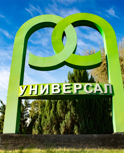 Вывеска компании Универсал на фоне зелёной территории